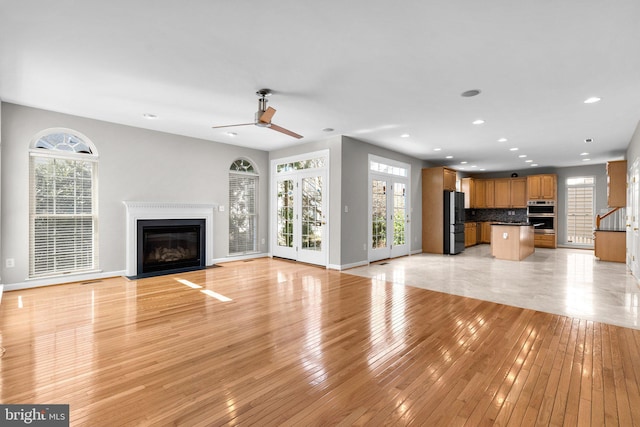 unfurnished living room with a fireplace with flush hearth, light wood-style flooring, recessed lighting, baseboards, and ceiling fan