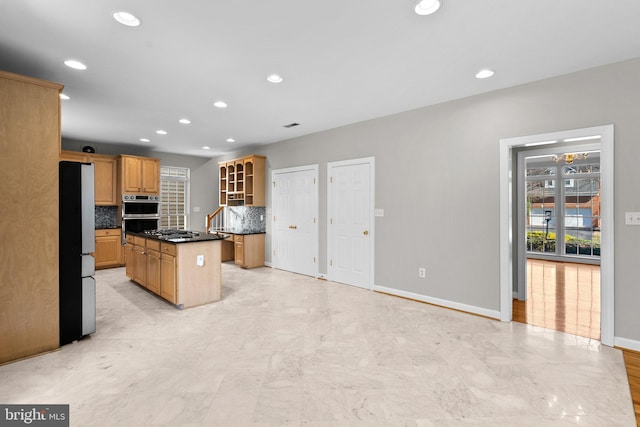 kitchen with dark countertops, a center island, decorative backsplash, recessed lighting, and appliances with stainless steel finishes