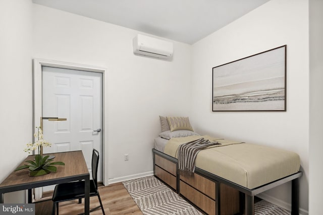 bedroom featuring hardwood / wood-style flooring and a wall unit AC