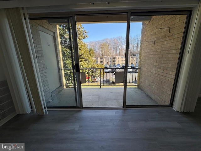 entryway with wood finished floors and brick wall