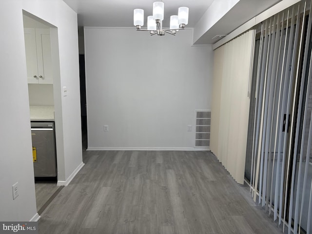 unfurnished dining area featuring a chandelier, visible vents, baseboards, and wood finished floors