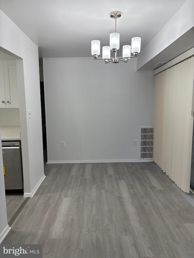 unfurnished dining area with visible vents, an inviting chandelier, baseboards, and wood finished floors