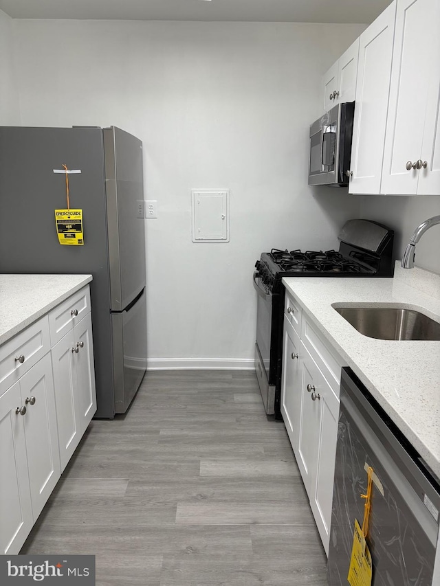 kitchen featuring a sink, appliances with stainless steel finishes, white cabinets, and light wood finished floors