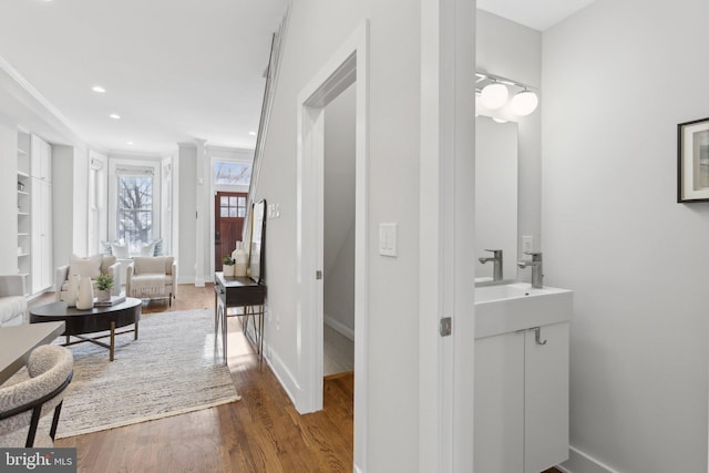 bathroom with sink, hardwood / wood-style floors, and crown molding