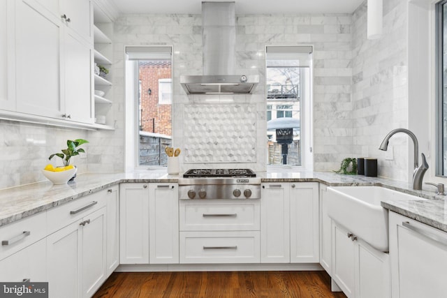 kitchen featuring sink, white cabinets, wall chimney exhaust hood, stainless steel gas stovetop, and light stone countertops