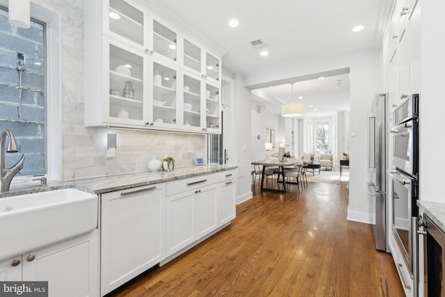 kitchen with tasteful backsplash, light stone countertops, pendant lighting, and white cabinetry