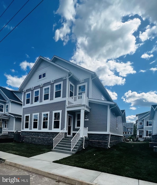 view of front of property featuring central AC unit, a balcony, and a front yard