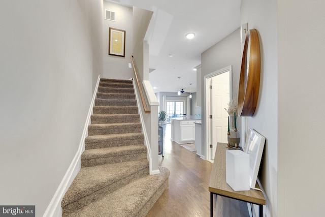 staircase with hardwood / wood-style floors and ceiling fan