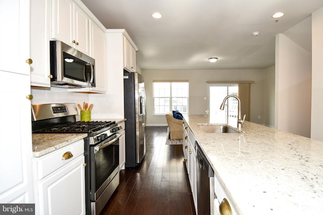 kitchen with sink, stainless steel appliances, white cabinets, and light stone countertops