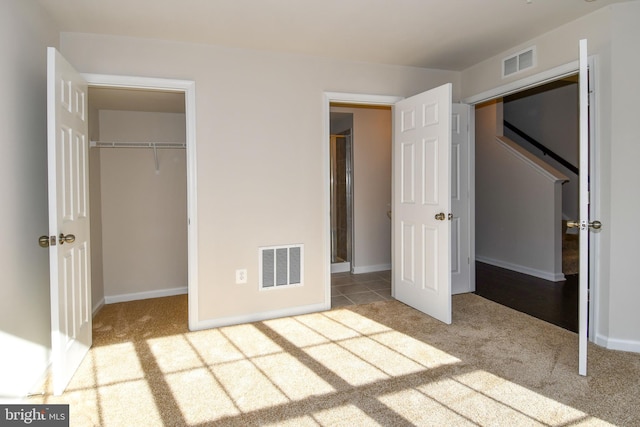 unfurnished bedroom with a spacious closet, light carpet, and a closet