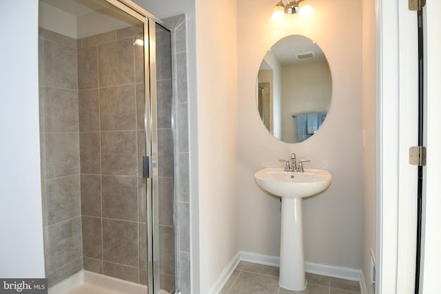 bathroom with a shower with shower door and tile patterned flooring