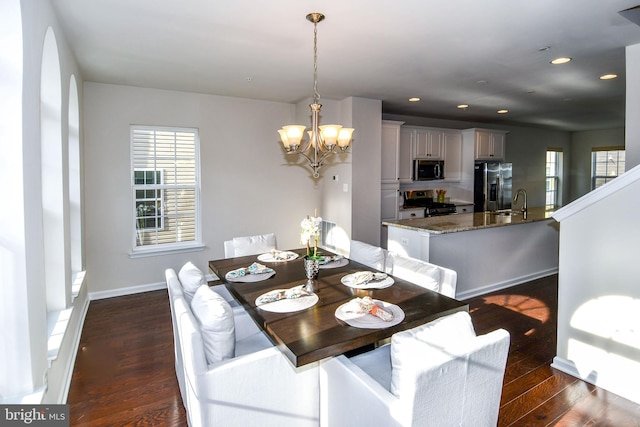 dining area featuring dark wood-type flooring, sink, and an inviting chandelier