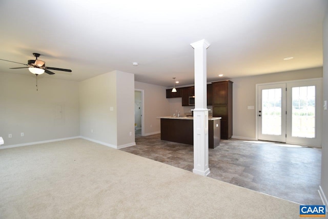 unfurnished living room with dark carpet, ceiling fan, and ornate columns