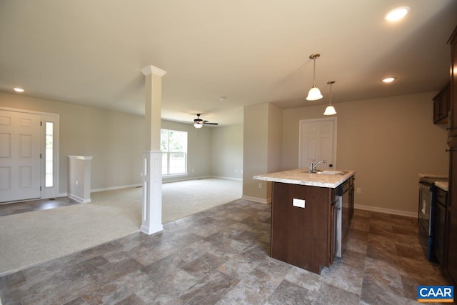 kitchen with ceiling fan, an island with sink, decorative light fixtures, light colored carpet, and dark brown cabinetry