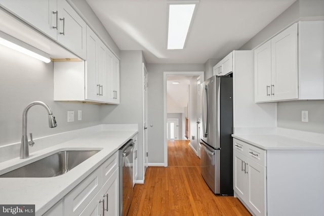 kitchen featuring white cabinets, stainless steel appliances, light hardwood / wood-style floors, and sink