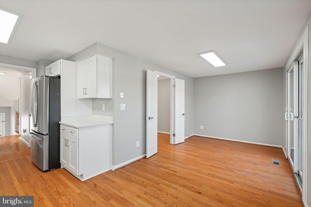 kitchen with white cabinetry, stainless steel fridge, and light wood-type flooring