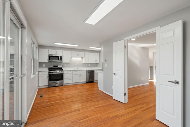 kitchen with sink, white cabinets, stainless steel appliances, and light wood-type flooring