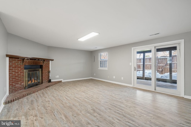 unfurnished living room featuring light hardwood / wood-style floors and a brick fireplace