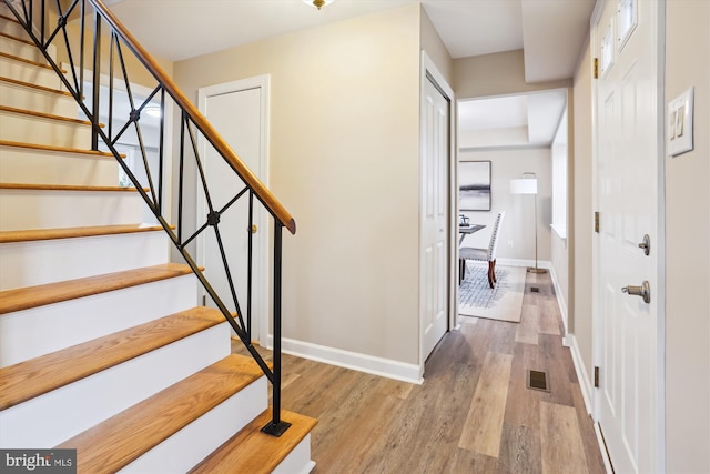 staircase featuring baseboards, visible vents, and wood finished floors