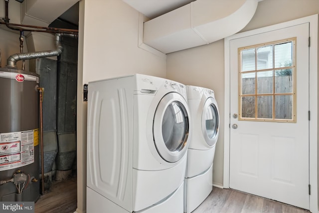 washroom featuring laundry area, light wood-style flooring, water heater, and washing machine and clothes dryer