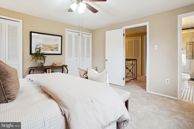 bedroom with light carpet, baseboards, a ceiling fan, ensuite bathroom, and two closets