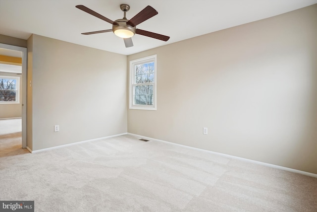 carpeted spare room featuring a ceiling fan and baseboards