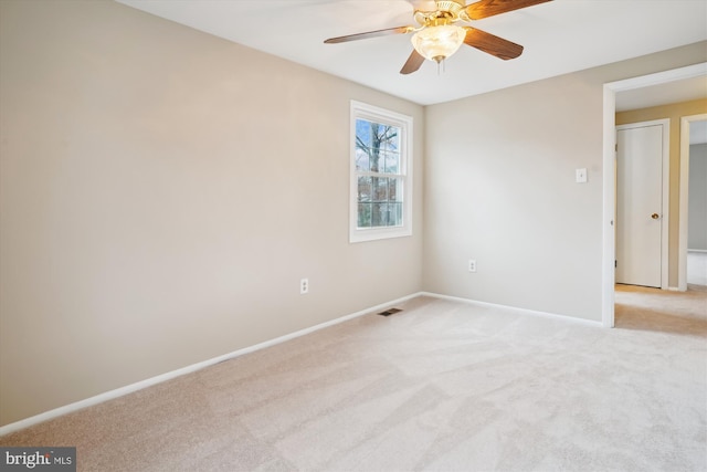 empty room featuring light carpet, ceiling fan, visible vents, and baseboards