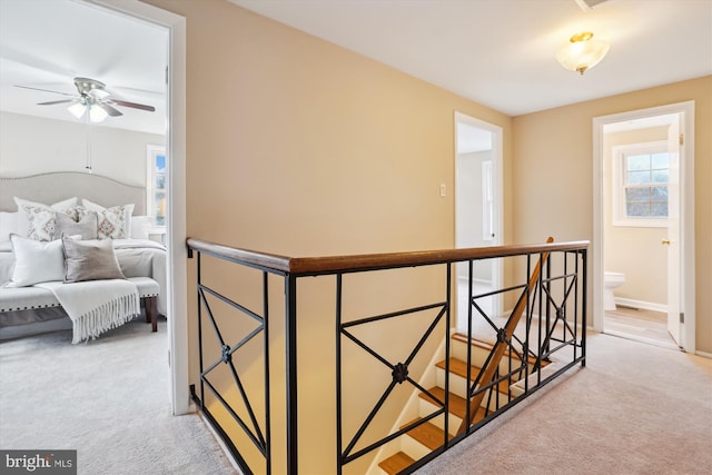 hall with baseboards, light colored carpet, and an upstairs landing