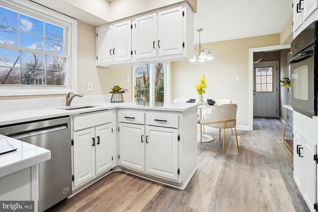 kitchen featuring a healthy amount of sunlight, light wood finished floors, dishwasher, and black oven