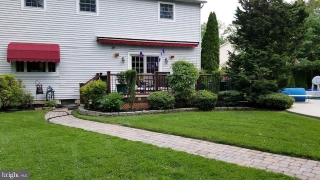 back of property featuring a wooden deck and a lawn