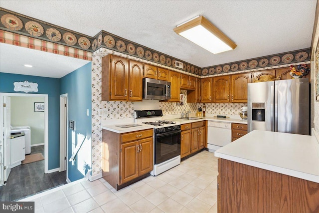 kitchen with stainless steel appliances, sink, a textured ceiling, and backsplash