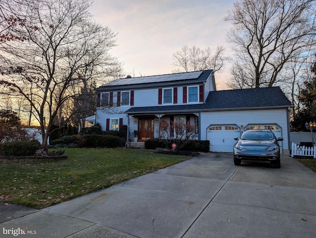 view of front of house with a yard, a garage, and solar panels