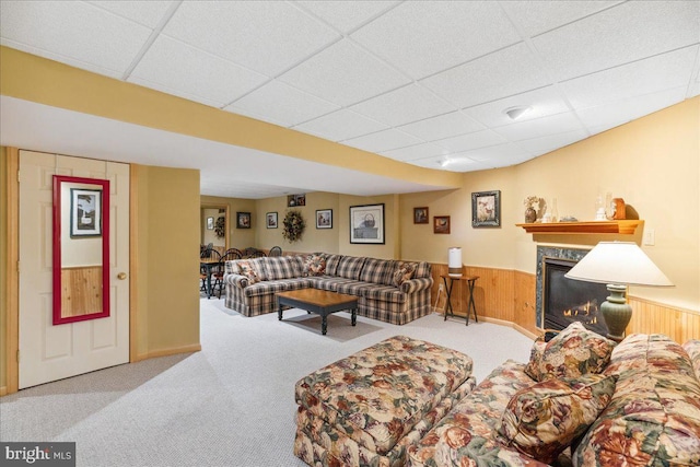 carpeted living room featuring a fireplace, a paneled ceiling, and wood walls