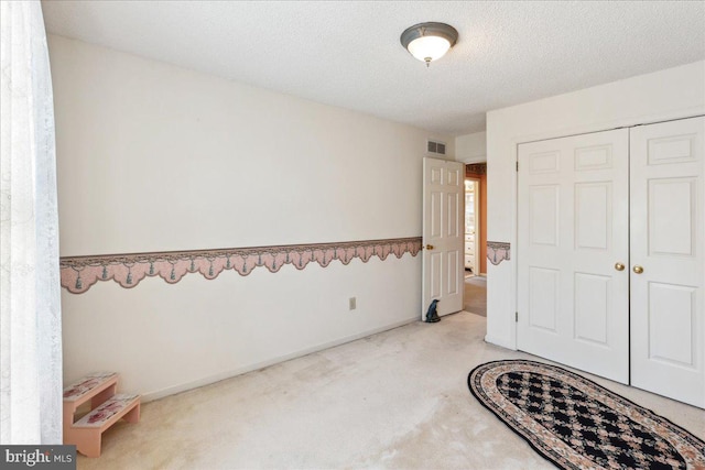 carpeted bedroom with a textured ceiling and a closet