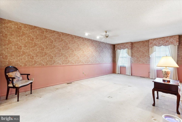 carpeted empty room with ceiling fan, plenty of natural light, and a textured ceiling