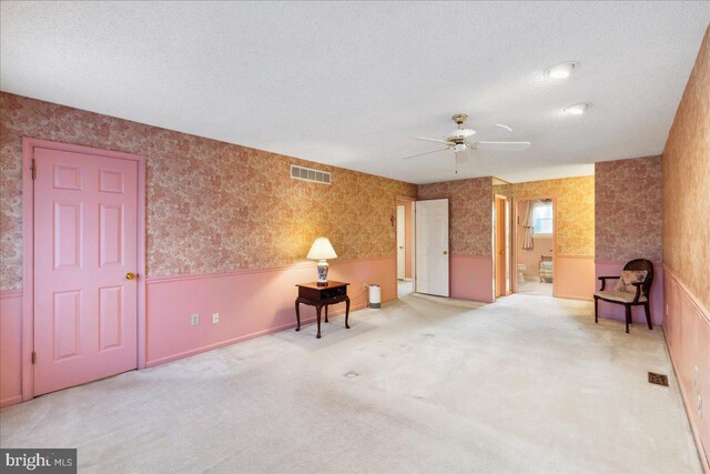 empty room with ceiling fan, carpet flooring, and a textured ceiling