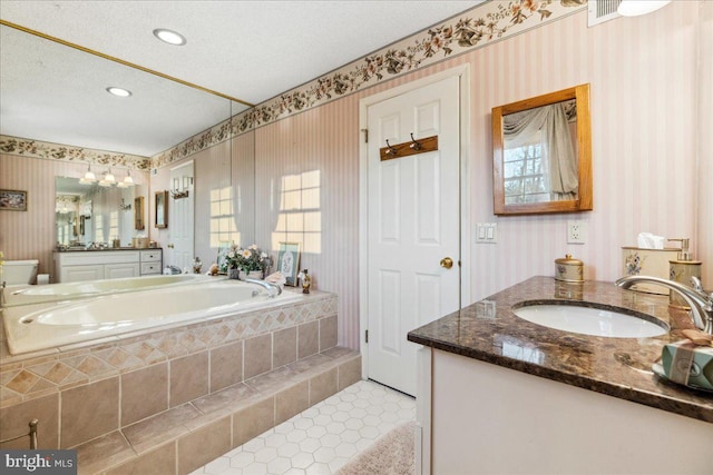 bathroom with tile patterned flooring, vanity, a relaxing tiled tub, and a textured ceiling