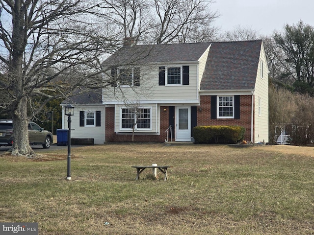 view of front of home featuring a chimney, a front lawn, and brick siding