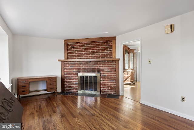 unfurnished living room with a fireplace, baseboards, and dark wood finished floors