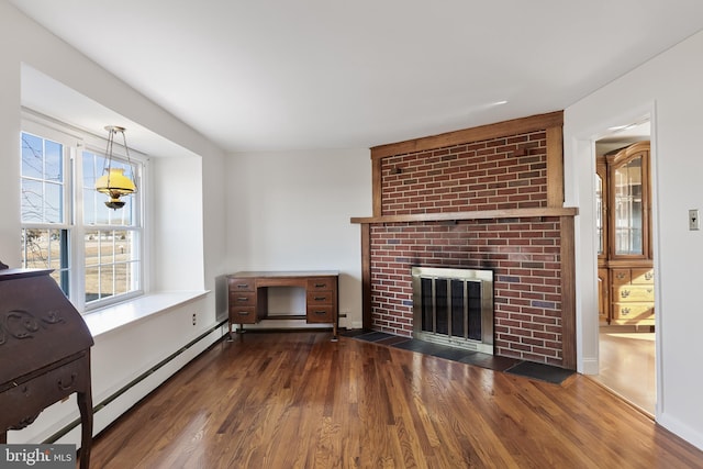 unfurnished living room with a brick fireplace, a baseboard heating unit, and dark wood-type flooring