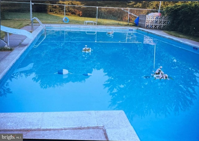 view of swimming pool with a fenced in pool, a water slide, fence, and a diving board