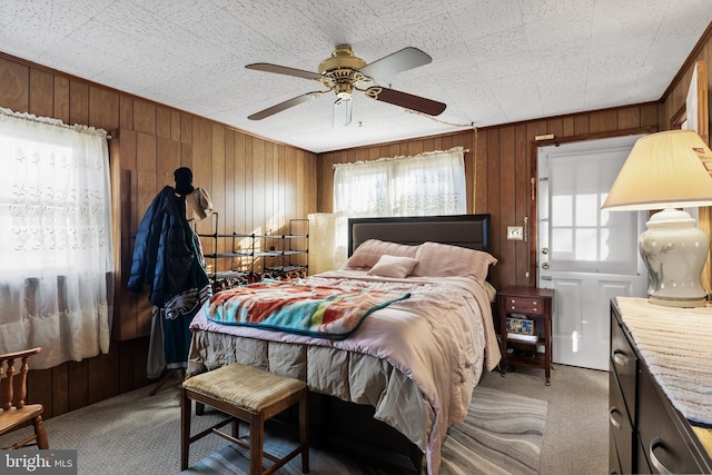 carpeted bedroom with a ceiling fan and wood walls