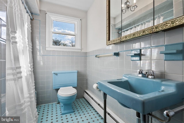 full bath with curtained shower, toilet, a wainscoted wall, a sink, and tile walls