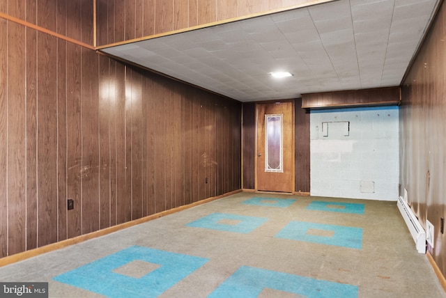 spare room featuring wooden walls, a baseboard heating unit, and carpet flooring