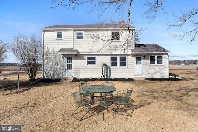 back of property with entry steps, a yard, and outdoor dining area