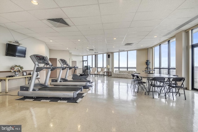 workout area with a paneled ceiling and a wall of windows