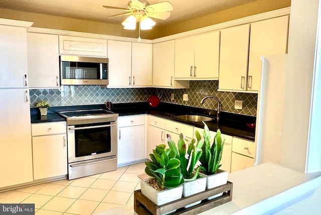 kitchen with decorative backsplash, appliances with stainless steel finishes, a textured ceiling, sink, and light tile patterned floors