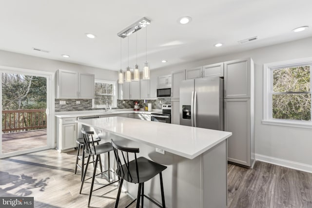 kitchen with appliances with stainless steel finishes, a center island, a breakfast bar area, and plenty of natural light