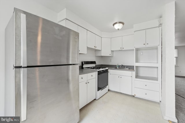 kitchen with stainless steel fridge, white gas range, sink, and white cabinetry