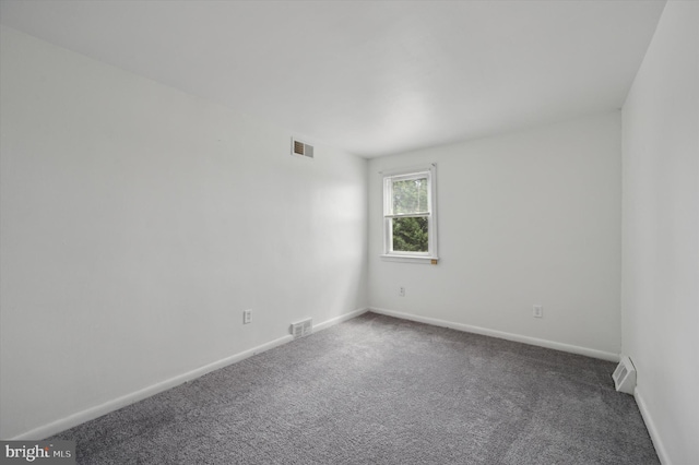 unfurnished room featuring dark colored carpet